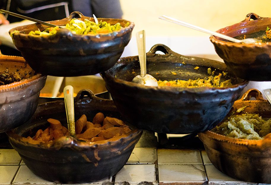 Clay pots of guisados at the counter of Tacos Hola El Güero